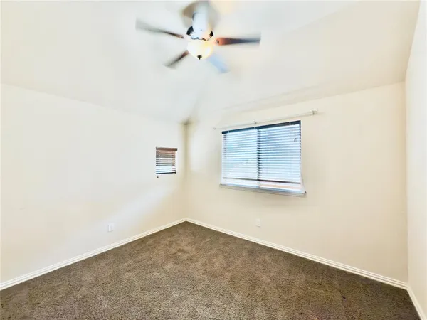 an empty room with a ceiling fan and carpet