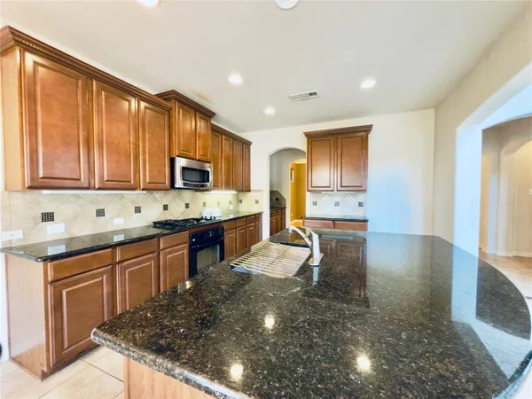 a view of kitchen with kitchen island stainless steel appliances refrigerator stove microwave and cabinets