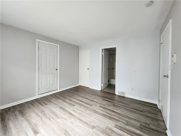 a view of an empty room with wooden floor and closet