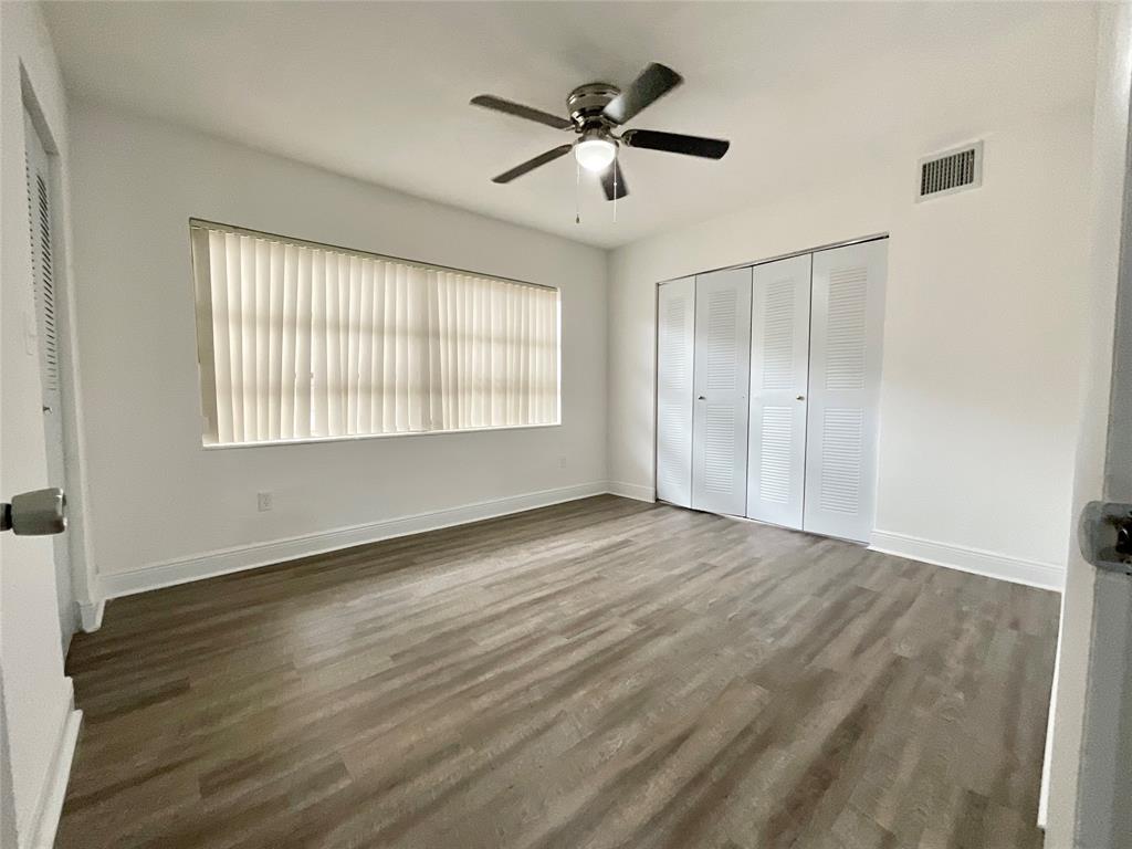 9357 Southwest 77th Avenue, Unit 853033 Miami, FL 33156 - Photo 4 of 17 a view of an empty room with wooden floor and a window