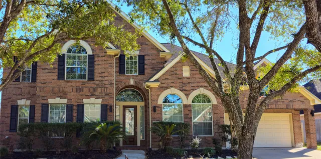 a front view of a house with large trees
