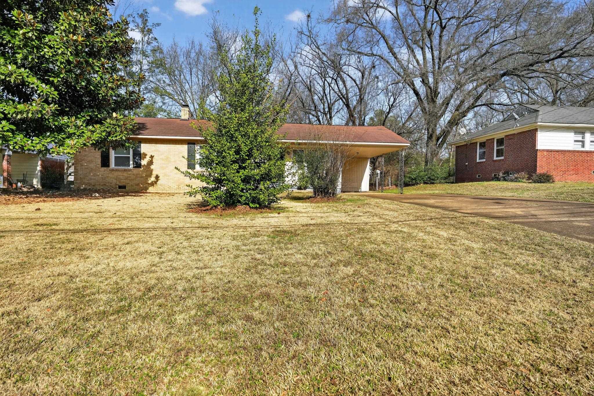 a front view of a house with a yard and trees