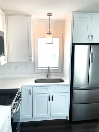 a kitchen with a sink a refrigerator a window and cabinets