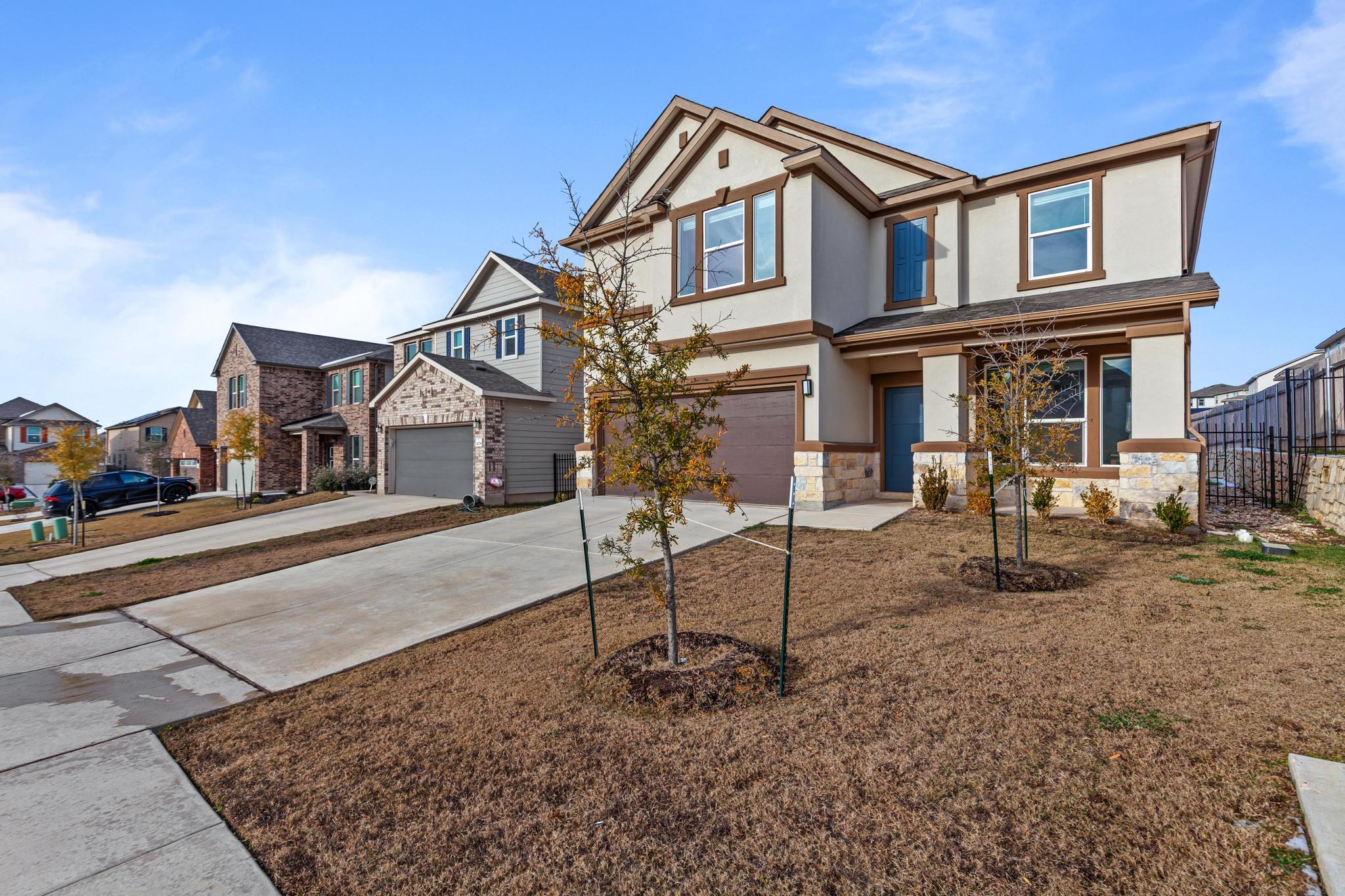 4712 Pear Light Rd Manor Manor, TX 78653 - Photo 2 of 39 View of front of property featuring driveway, stucco siding, an attached garage, stone siding, and a residential view