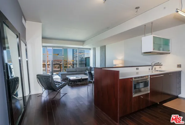 a kitchen with stainless steel appliances granite countertop a refrigerator a stove a sink dishwasher a dining table and chairs with wooden floor