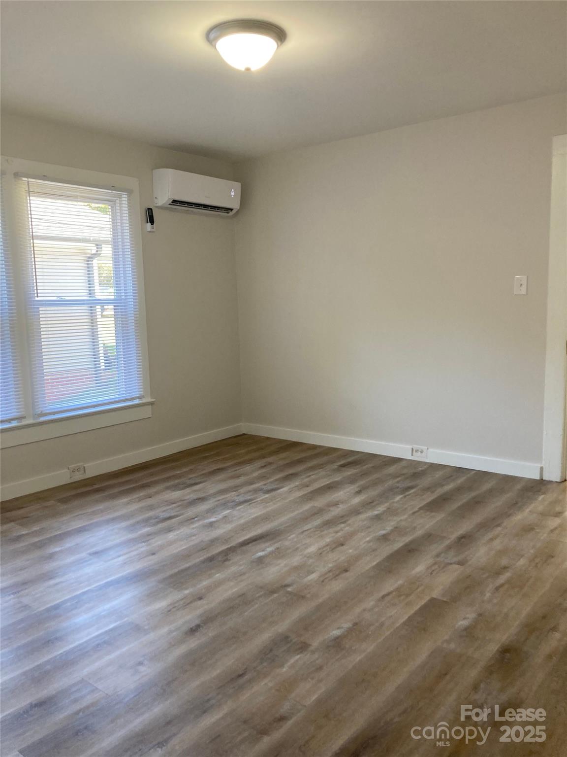 654 Wilson Street Kannapolis, NC 28083 - Photo 8 of 15 an empty room with wooden floor and windows