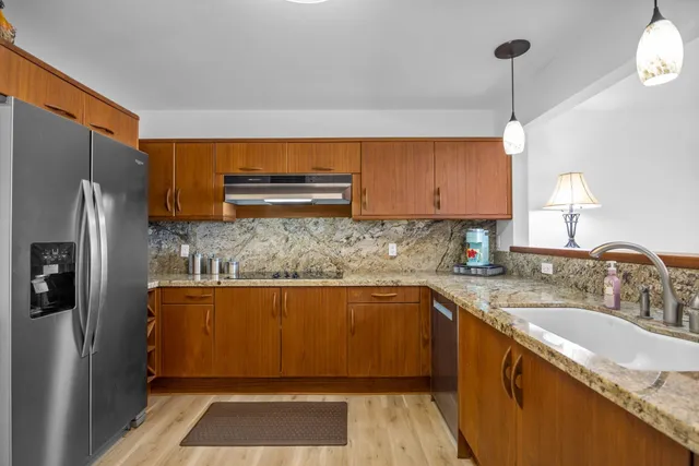 a kitchen with stainless steel appliances granite countertop a sink refrigerator and cabinets
