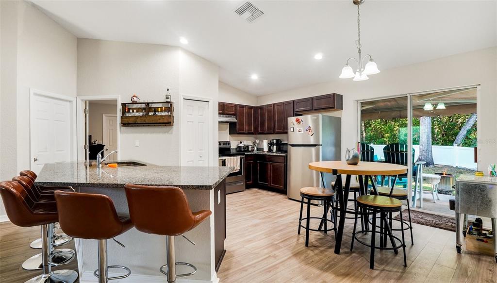 6201 East Peach Street Inverness, FL 34452 - Photo 8 of 30 a kitchen with stainless steel appliances granite countertop a stove a refrigerator a sink a dining table and chairs with wooden floor