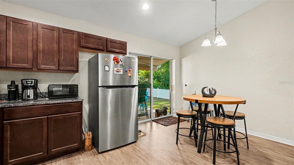 6201 East Peach Street Inverness, FL 34452 - Photo 9 of 30 a kitchen with stainless steel appliances granite countertop a refrigerator a stove a sink dishwasher and a dining table with wooden floor