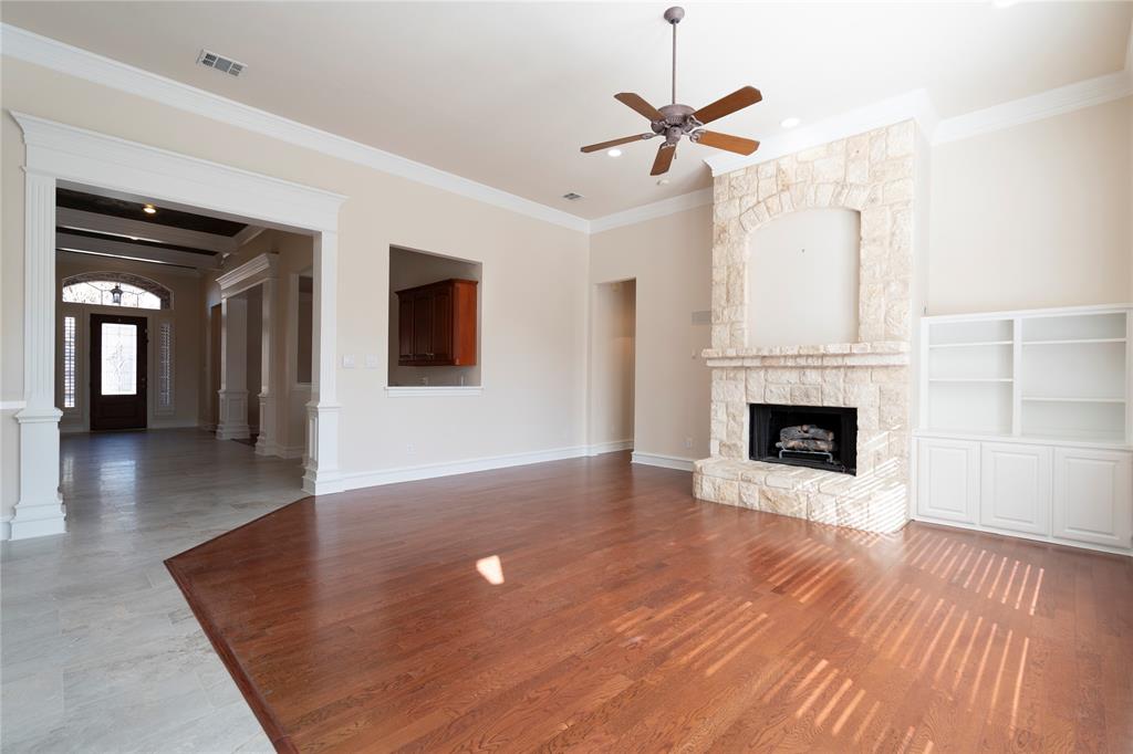 1425 Kingsmill Court Coppell, TX 75019 - Photo 15 of 30 an empty room with wooden floor a ceiling fan a fireplace and windows