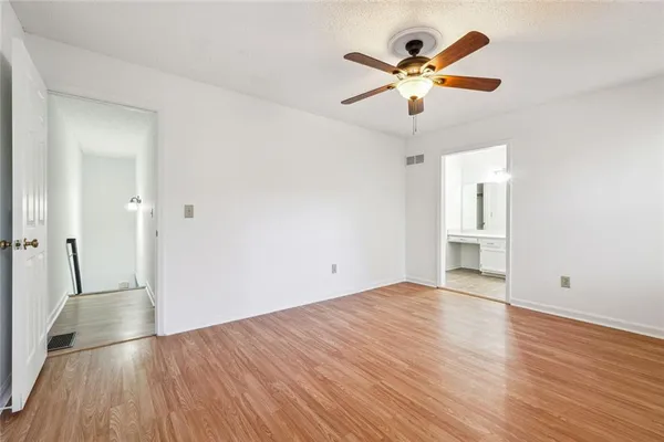 an empty room with wooden floor and ceiling fan