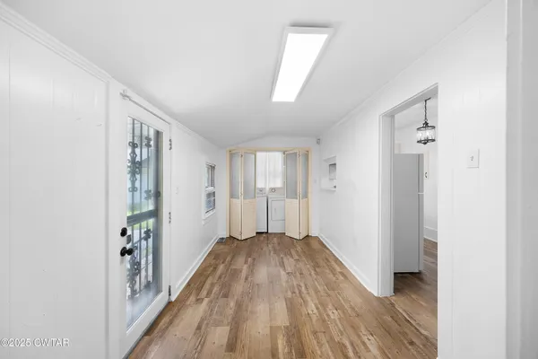 a view of a hallway with wooden floor and a bathroom