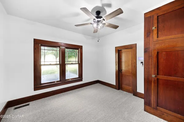 an empty room with windows and fan