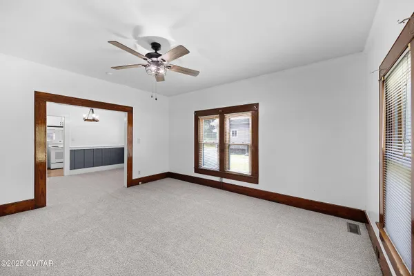 an empty room with windows and fan