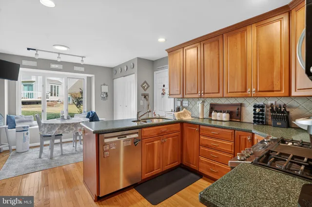 a kitchen with stainless steel appliances granite countertop a stove a sink dishwasher and cabinets with wooden floor