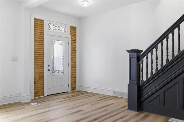 a view of an empty room with window and wooden floor