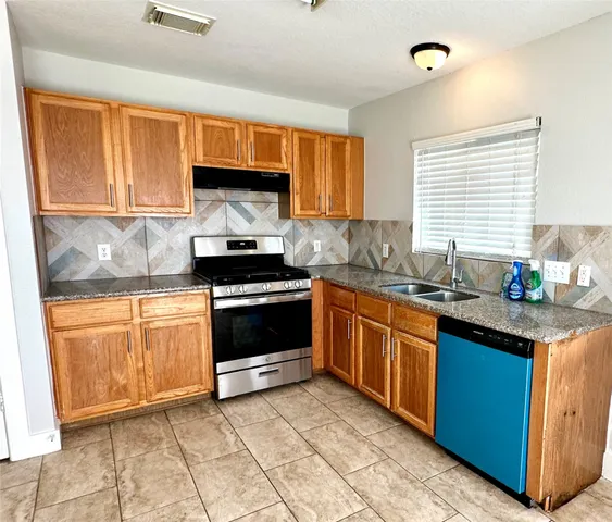 a kitchen with stainless steel appliances granite countertop a stove a sink and a microwave