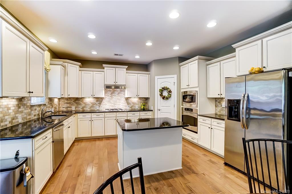 692 Old Cove Road Tega Cay, SC 29708 - Photo 14 of 44 a kitchen with stainless steel appliances granite countertop a refrigerator a stove top oven a sink dishwasher and white cabinets with wooden floor