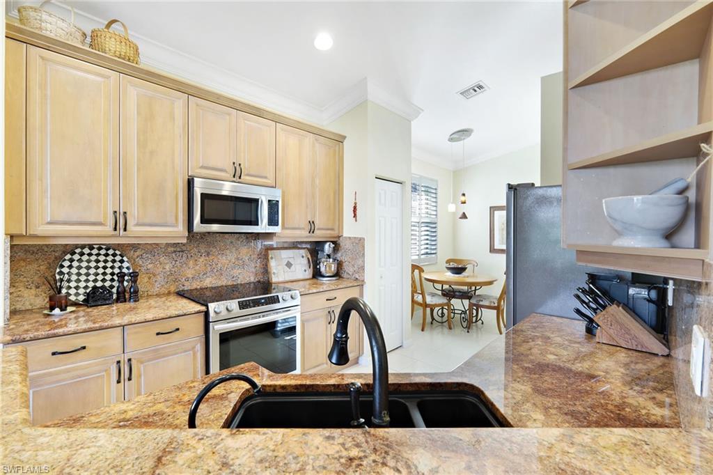 9354 Springview Loop Estero, FL 33928 - Photo 9 of 30 a kitchen with granite countertop a stove a sink a counter space and cabinets