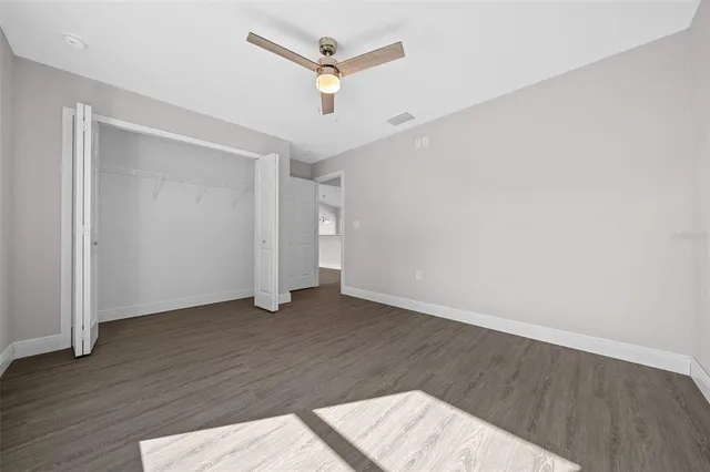 an empty room with wooden floor and ceiling fan