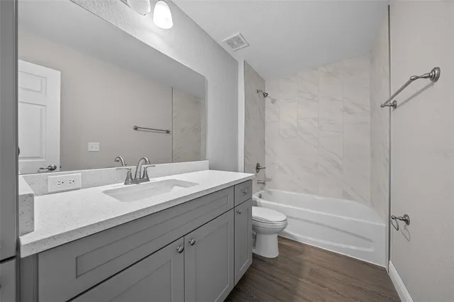 a bathroom with a granite countertop sink a toilet and a bathtub