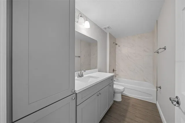 a bathroom with a granite countertop sink a toilet and shower