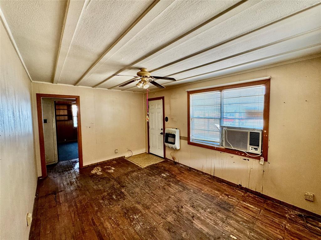413 East Locust Street Whitewright, TX 75491 - Photo 4 of 16 Unfurnished room with dark wood-type flooring, a ceiling fan, heating unit, and a textured ceiling