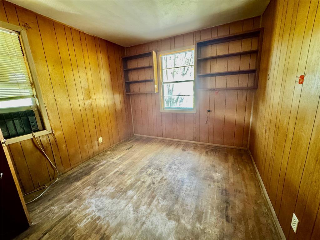 413 East Locust Street Whitewright, TX 75491 - Photo 6 of 16 Spare room featuring hardwood / wood-style floors, wooden walls, and cooling unit