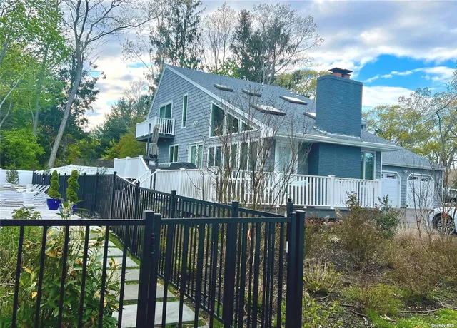 a view of a house with wooden fence next to a yard
