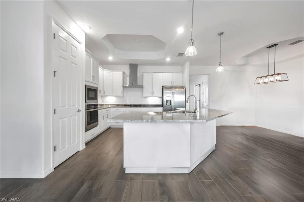 43240 Boardwalk Loop Punta Gorda, FL 33982 - Photo 13 of 41 a large kitchen with stainless steel appliances kitchen island a large counter top and wooden floors