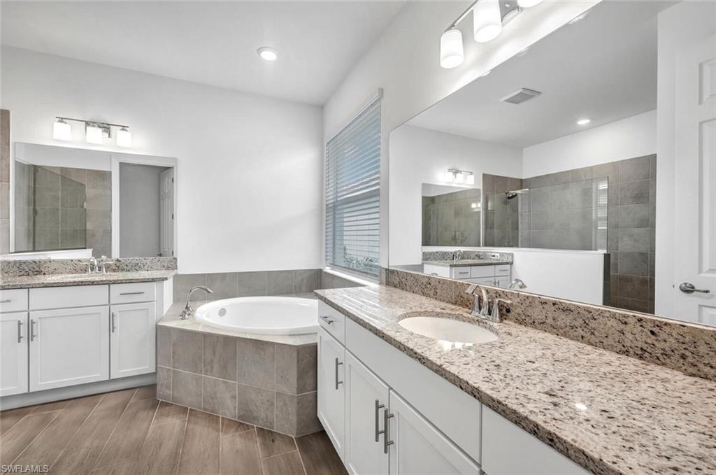 43240 Boardwalk Loop Punta Gorda, FL 33982 - Photo 19 of 41 a bathroom with a granite countertop double vanity sink and mirror with bathtub