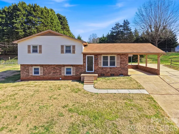 a view of a house with a yard and large tree