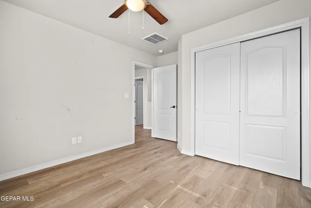 an empty room with wooden floor and ceiling fan