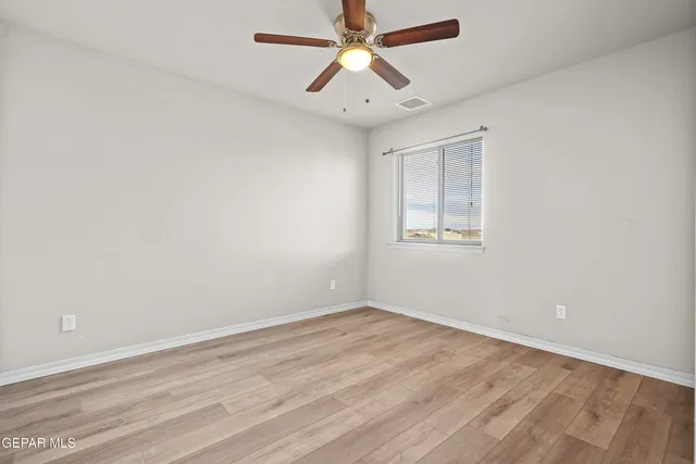 an empty room with a window and a fan