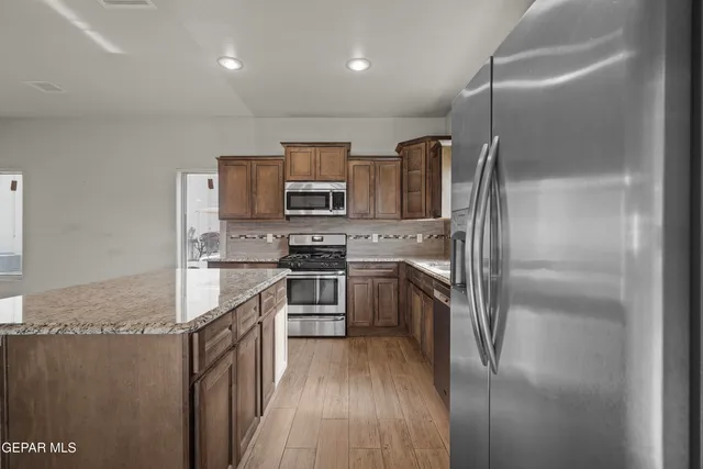 a kitchen with kitchen island a counter top space stainless steel appliances and cabinets