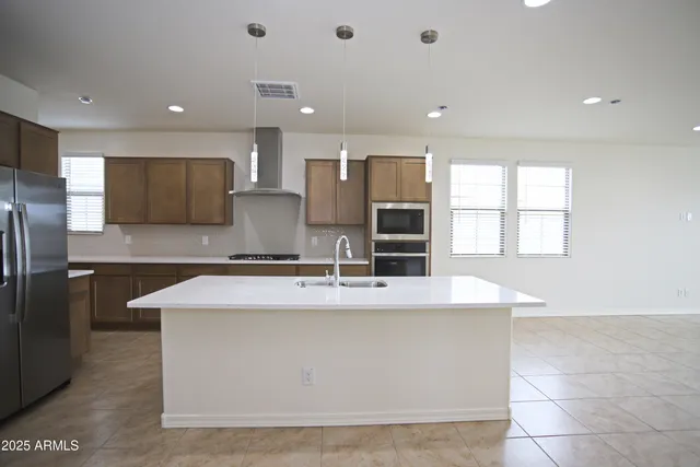 a large kitchen with kitchen island a stove a sink a refrigerator and a dining table