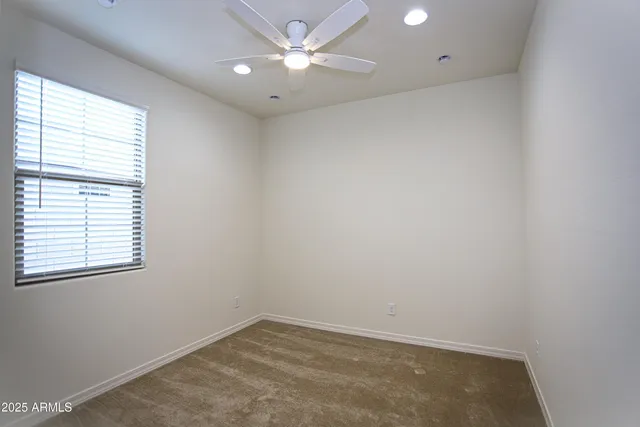 an empty room with a window and ceiling fan