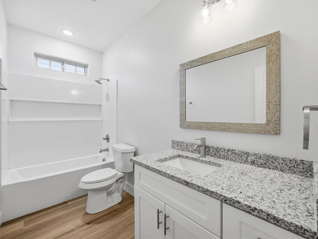 108 Couch Street Italy, TX 76651 - Photo 18 of 23 a bathroom with a granite countertop toilet a sink and a mirror