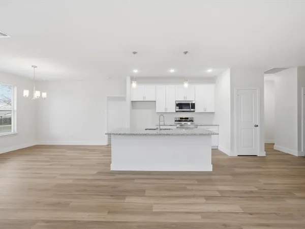 a view of kitchen with kitchen island stainless steel appliances wooden cabinets and granite counter tops