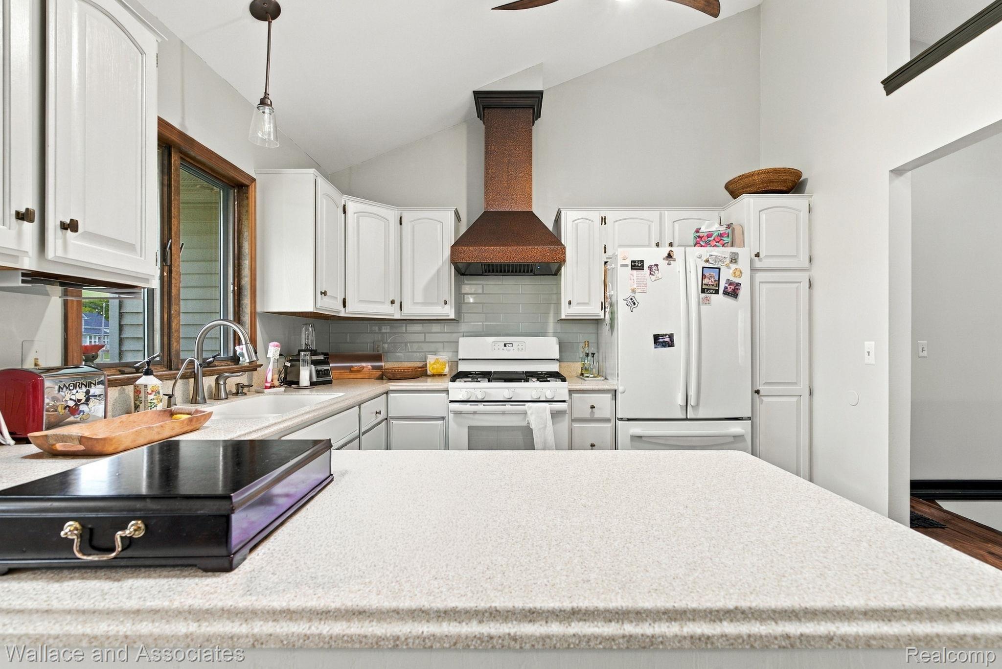 17076 27 Mile Road Ray, MI 48096 - Photo 16 of 63 Kitchen featuring white cabinetry, light-toned countertops, a tile backsplash, and a vaulted ceiling