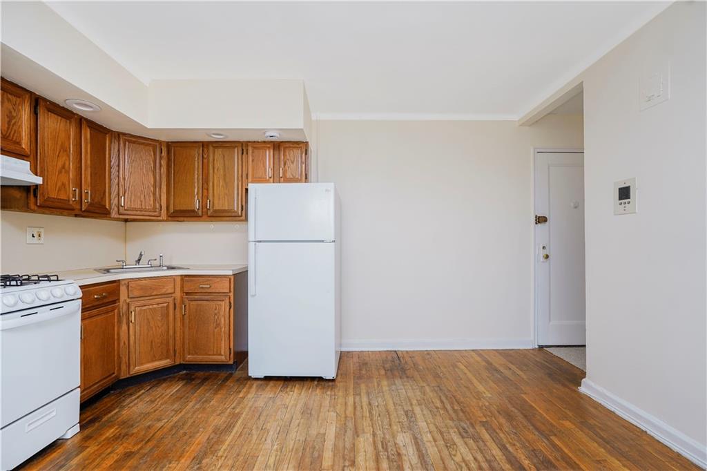 9430 Ridge Boulevard, Unit 6F Brooklyn, NY 11209 - Photo 11 of 15 a kitchen with a refrigerator a stove top oven a sink and dishwasher with wooden floor