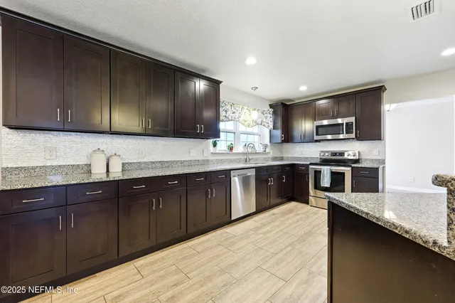 a kitchen with stainless steel appliances granite countertop wooden cabinets a stove top oven a sink and dishwasher