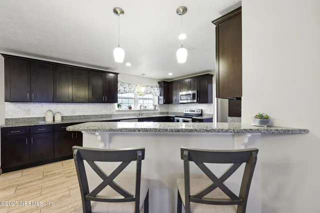 a kitchen with stainless steel appliances kitchen island granite countertop a stove a sink and a microwave