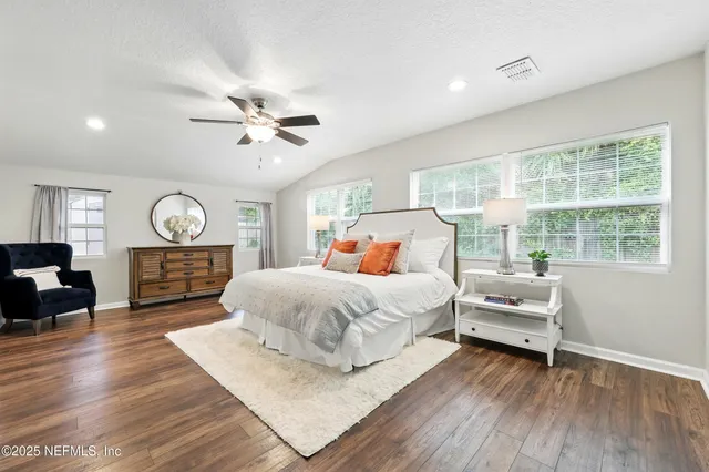 a bedroom with a bed a dresser and wooden floor