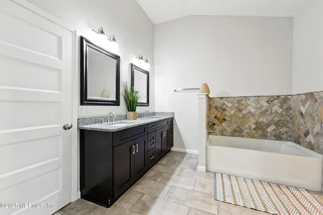 a bathroom with a double vanity sink mirror and bathtub