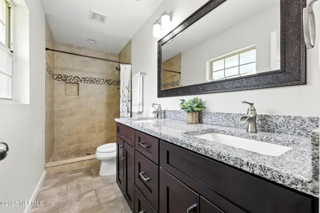 a bathroom with a granite countertop sink mirror vanity and toilet