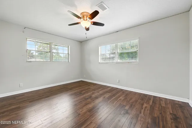 an empty room with wooden floor and windows