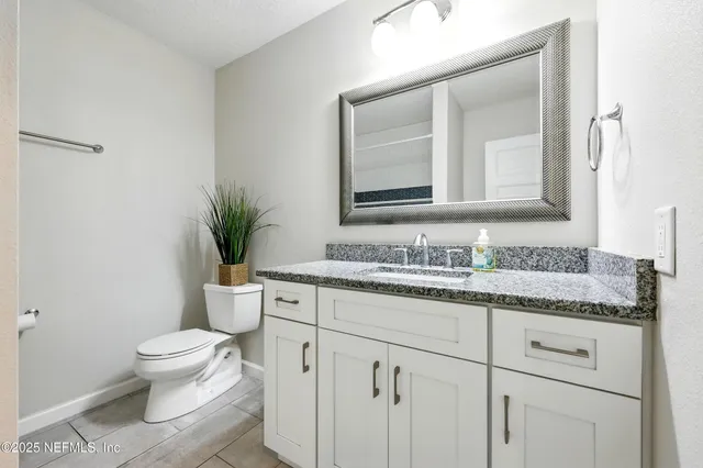 a bathroom with a granite countertop sink a toilet and a mirror