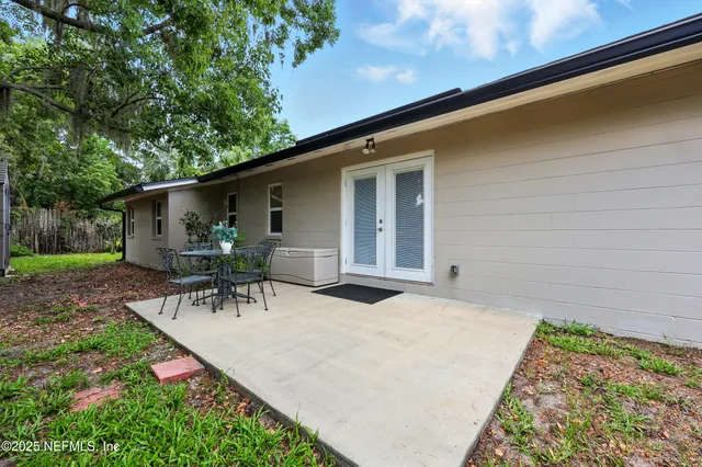 a view of backyard with table and chairs and potted plants