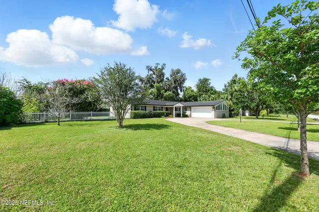 a view of a house with a big yard and a large tree